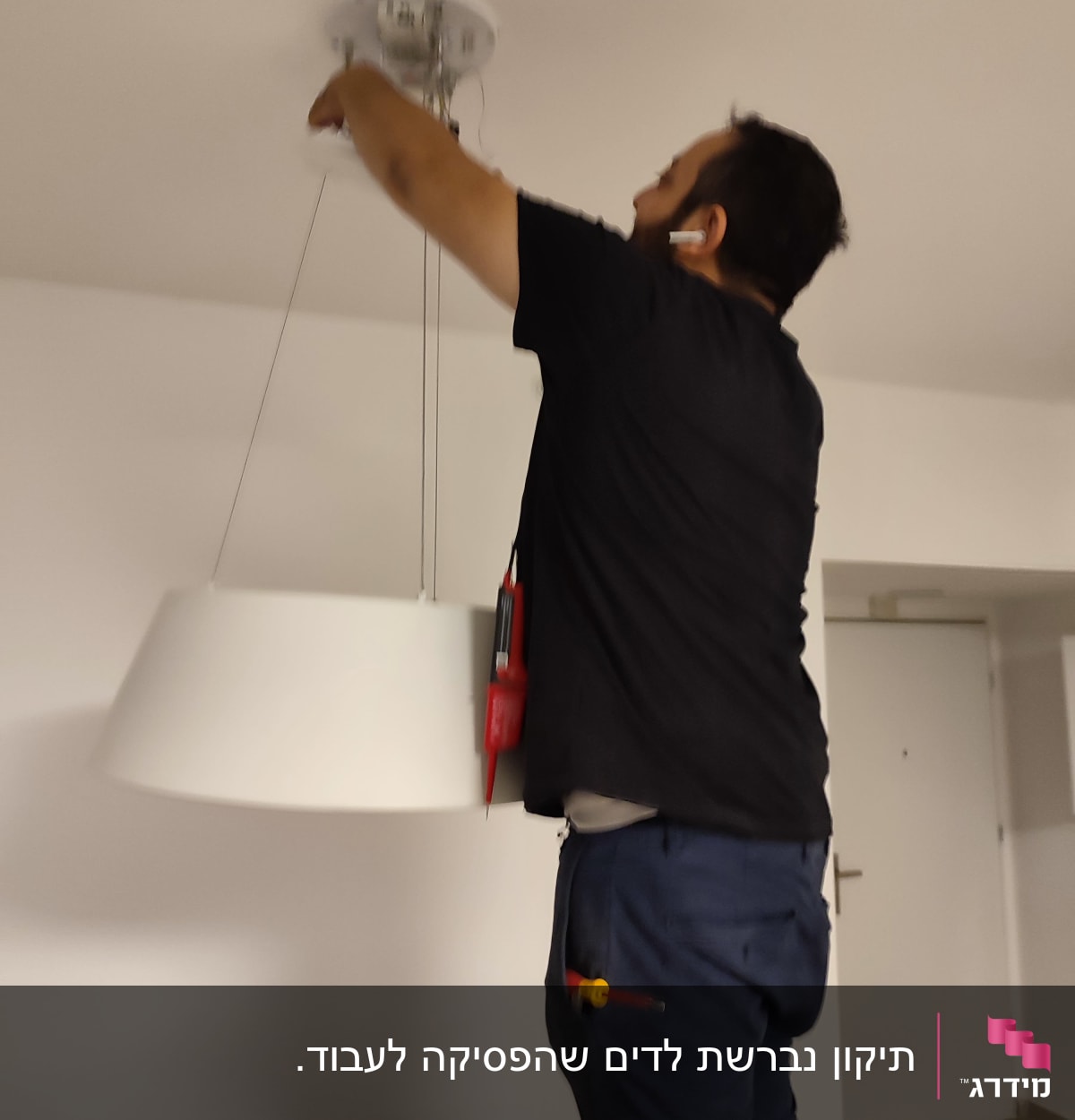 חשמלאי מתקין מנורה בתקרה עם מברג ביד